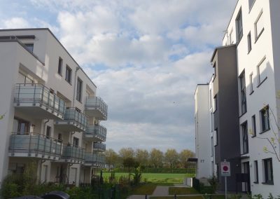 Mehrfamilienhäuser in Fellbach, Durchblick zwischen Hauszugang und Balkone auf das freie Feld